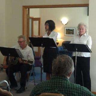A small group of people performing in front of an audience indoors.