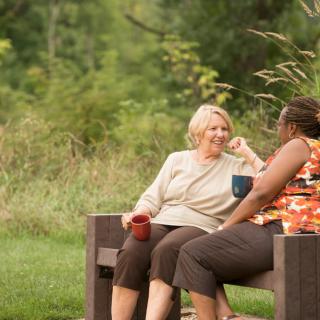 Two people enjoying a conversation on a park bench.