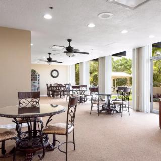 A bright and airy indoor dining area with multiple tables and chairs, illuminated by natural light.