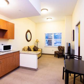 A cozy apartment living area featuring a kitchenette, sofa, and dining table.