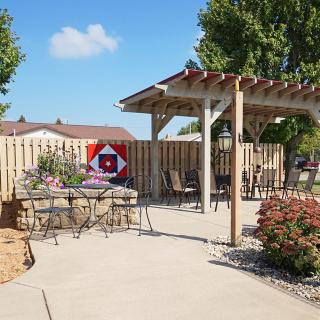 A tranquil patio area featuring a pergola, outdoor seating, and well-maintained landscaping.