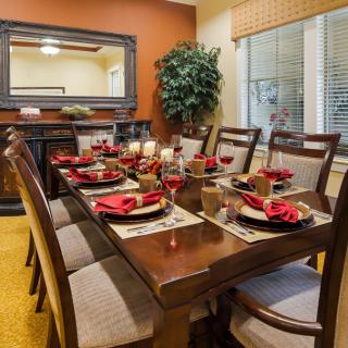 A beautifully set dining table with elegant dinnerware and red napkins, creating a warm and inviting atmosphere.