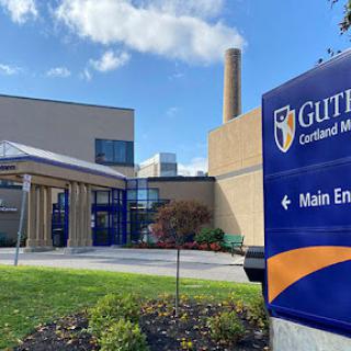 The main entrance of Guttman Medical Center, showcasing modern architecture and signage.