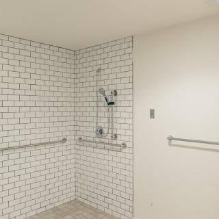 A modern minimalist bathroom with white subway tiles and handrails.