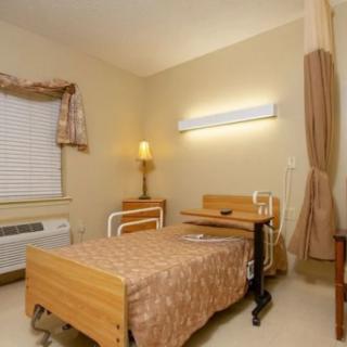 A hospital room with a bed, medical equipment, and a window with curtains.