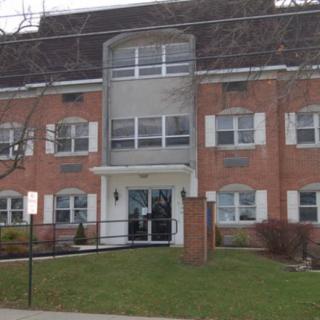 A small brick apartment building with a central entrance and multiple windows.