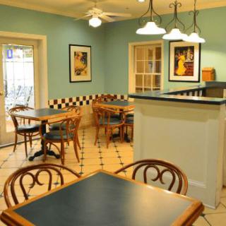A cozy cafe interior with tables and chairs, decorated with artwork and warm lighting.