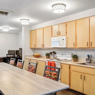 A spacious kitchen with wooden cabinets, a long dining table, and modern lighting fixtures.