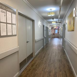 A long, well-lit hallway with multiple doors, typically found in an institutional setting.