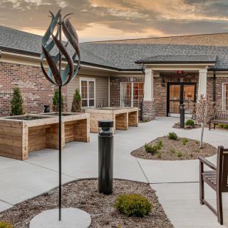 A modern building entrance with an abstract sculpture and landscaped surroundings.