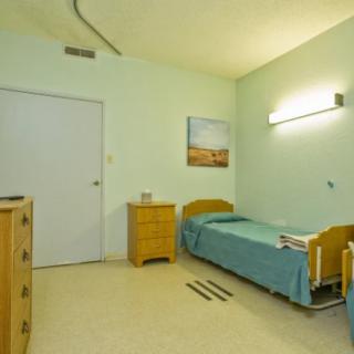 A simple hospital room with a bed and basic furniture.