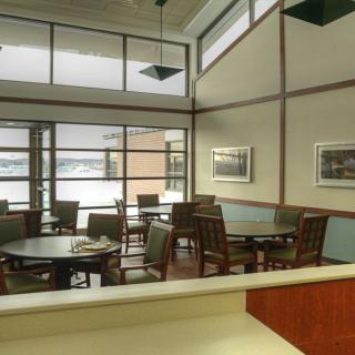 A modern dining area with wooden furniture and large windows providing natural light.