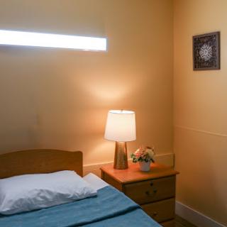 A cozy bedroom featuring a neatly made bed, a bedside lamp, and decorative elements on the wall.