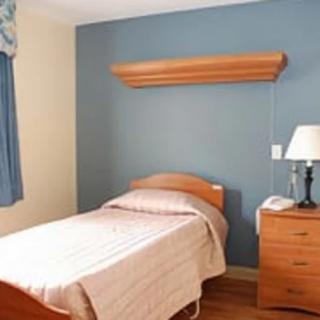 A simple bedroom with a single bed, nightstand, and lamp.