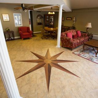 A cozy living room features a unique compass rose design on the floor, with comfortable furniture and decorative columns.