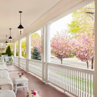 A serene porch with white chairs overlooking blossoming trees in spring.