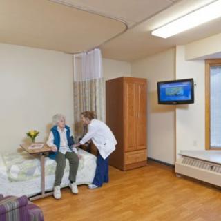 A nurse attending to an elderly patient in a hospital room.