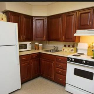 A cozy kitchen with dark wooden cabinets, a stove, refrigerator, and microwave.