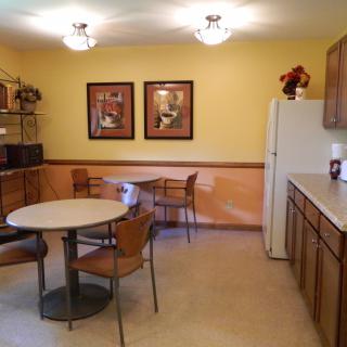 A cozy kitchen and dining area with wooden cabinets and round tables.