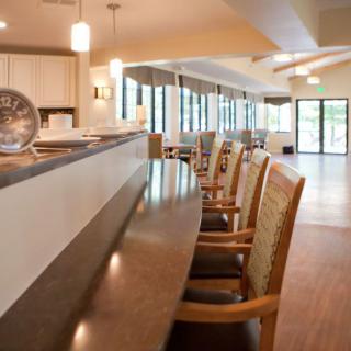 A modern kitchen interior with a sleek counter and comfortable chairs, illuminated by pendant lighting.