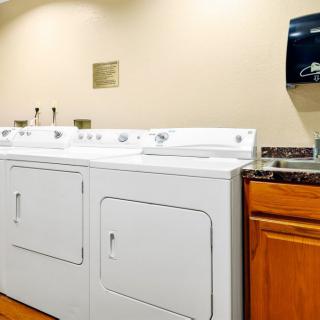 A laundry room featuring a washing machine, dryer, and countertop with cabinets.