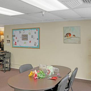 A small meeting room with a conference table and chairs, featuring a bulletin board and artwork on the walls.