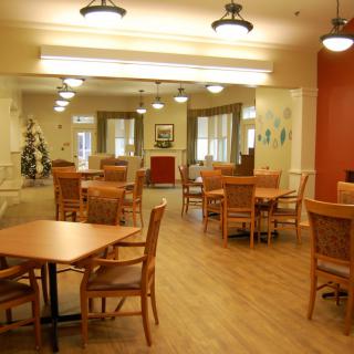 A spacious dining area with wooden tables and chairs, well-lit with elegant ceiling lights.