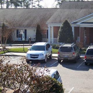 A view of a parking lot with various vehicles parked outside a building.