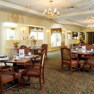 A cozy dining room with elegantly set tables and warm lighting.