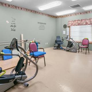 A rehabilitation room equipped with exercise machines and chairs for physical therapy.