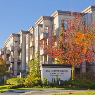 A residential apartment building with autumn trees and a clear blue sky.