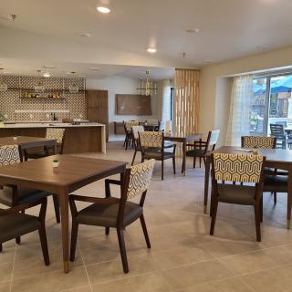 A modern dining area with tables and chairs, adjacent to a kitchen space.