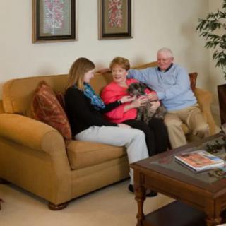 A family sitting together on a sofa in a cozy living room with their pet dog.