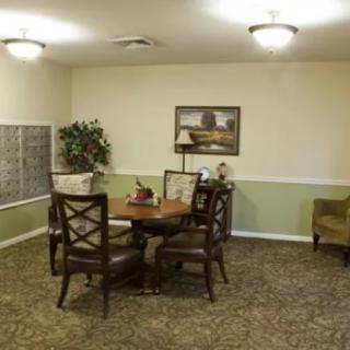 Cozy living room with a round table and chairs, decorated with a painting and lamp.