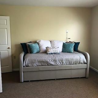 A minimalist bedroom featuring a stylish daybed with decorative pillows and neutral tones.