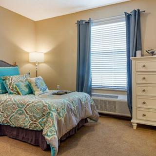 A cozy bedroom with a neatly made bed, stylish bedding, and a white dresser.