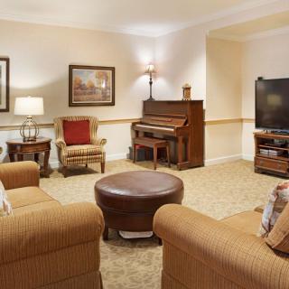 A cozy living room featuring a piano, comfortable seating, and a TV.
