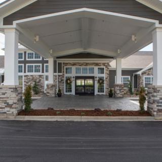 Front entrance of a modern building with stone facade and covered driveway.