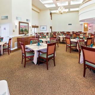A spacious dining area with neatly arranged tables and chairs, featuring a chandelier and elegant decor.