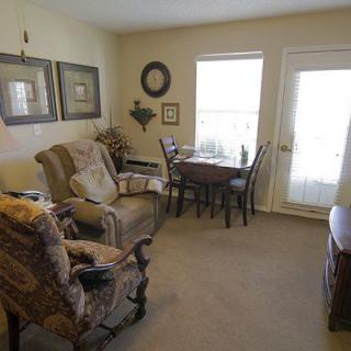 A cozy living room with comfortable seating, a small dining table, and wall decor.