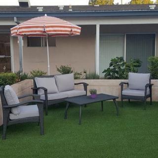 A cozy patio setup with outdoor furniture and a striped umbrella on a green lawn.