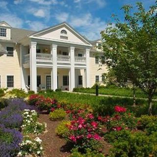 A picturesque building with classical columns surrounded by a vibrant garden.