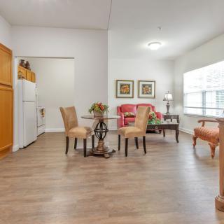 A bright and spacious living room with a dining area, featuring hardwood floors, stylish furniture, and large windows.