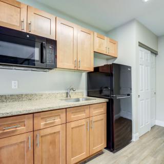 Modern kitchen with wooden cabinets, a microwave, and a small fridge.