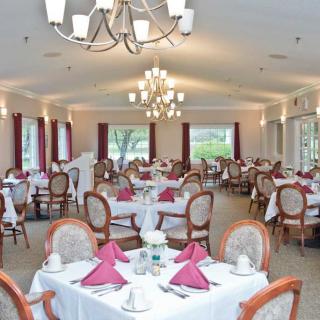 An elegant dining room with neatly arranged tables and chairs, set for a formal meal.