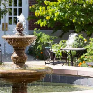 A beautiful garden with a flowing fountain on a sunny day.