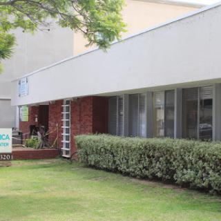 A modern building facade with a well-maintained lawn and shrubs.