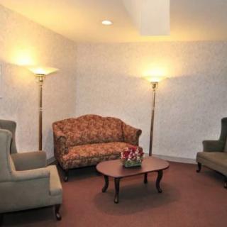 A cozy living room with a sofa, two armchairs, a wooden coffee table, and floor lamps.