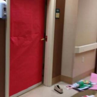 A door covered with red paper in a hospital hallway, with scattered items on the floor.