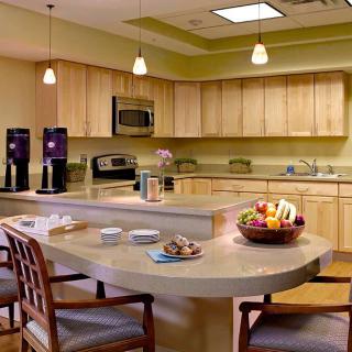 A modern kitchen with a dining area, featuring wood cabinets and a spacious countertop.